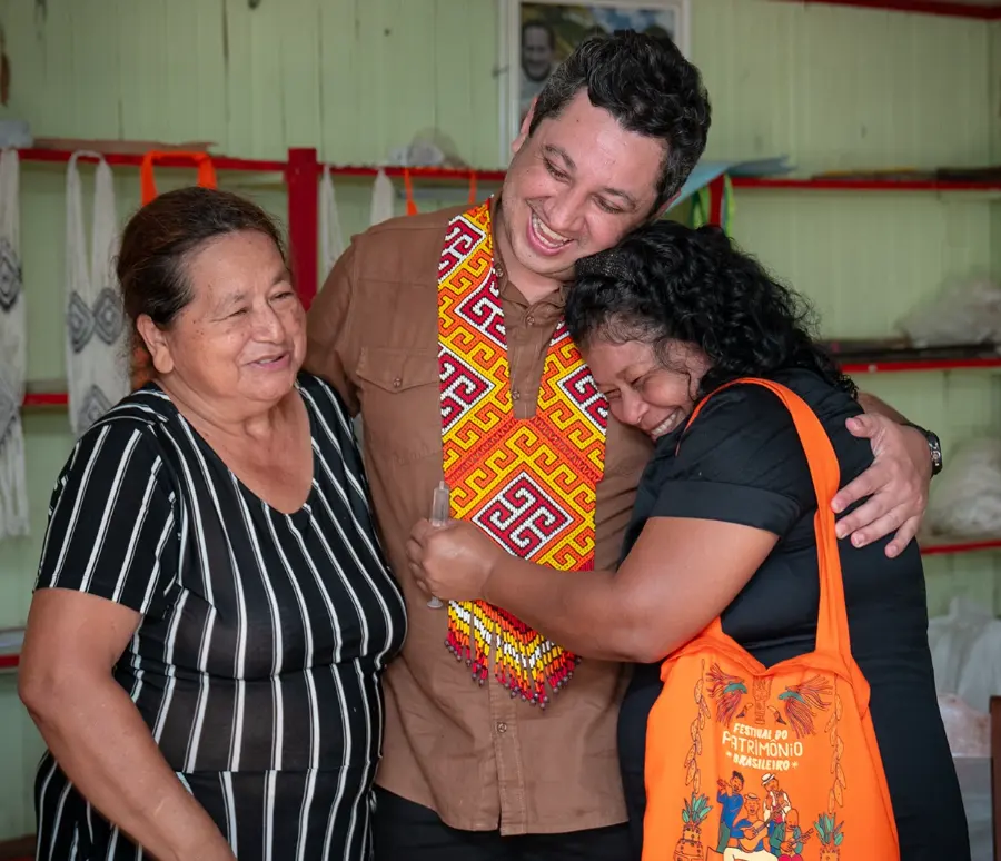 Tiago Mourão abraçado por duas moradoras